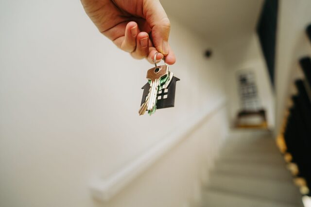 A hand holding a house-shaped keyring after signing a lease.